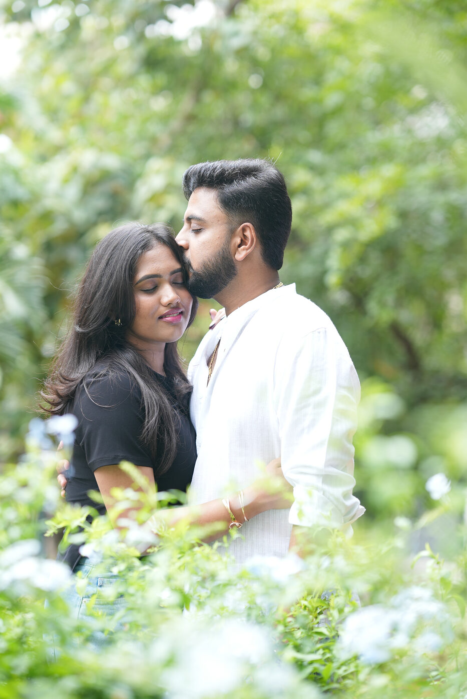 Navya and Subramanya sharing a gentle forehead kiss in a garden