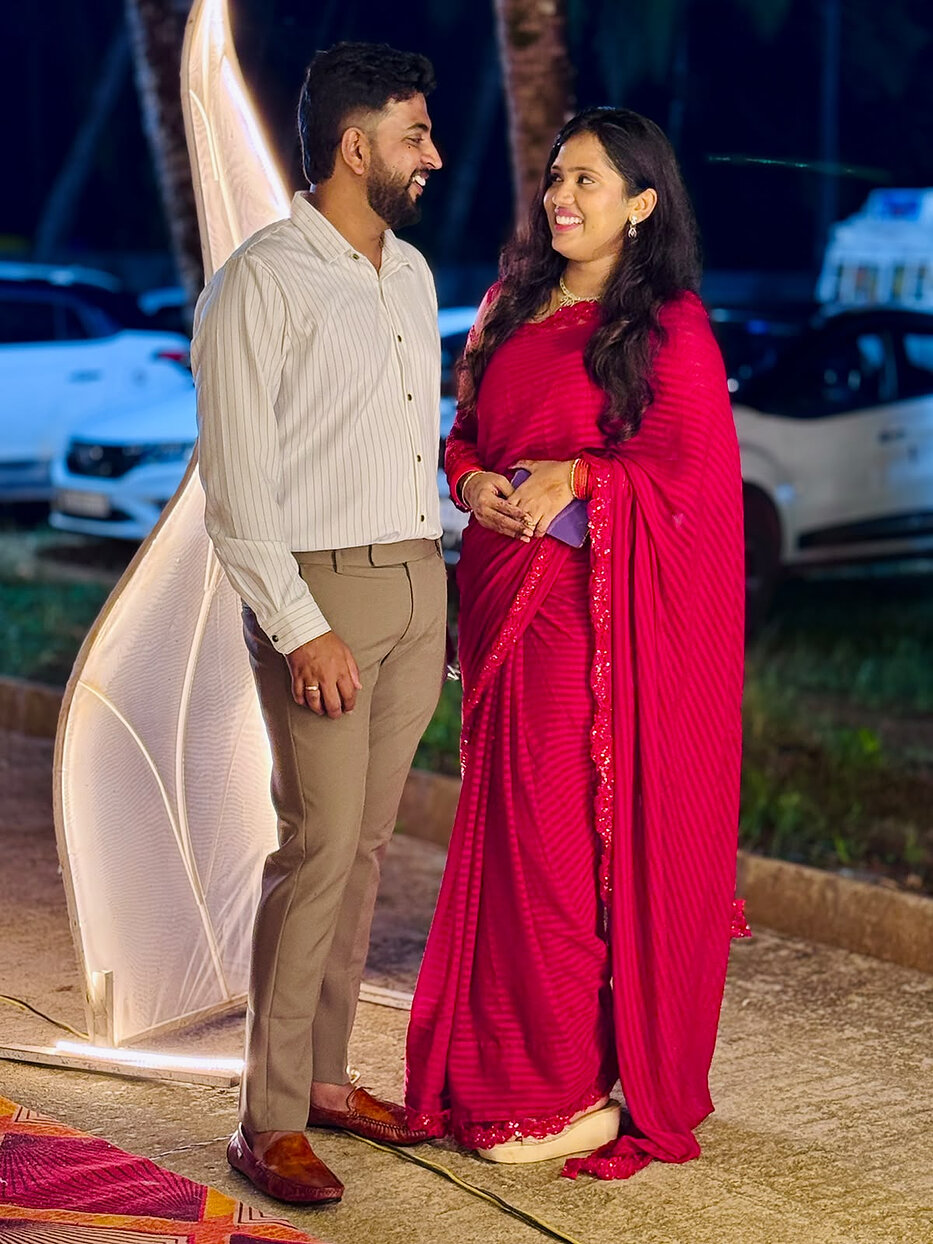 Navya in a red saree and Subramanya in a striped shirt at an evening celebration