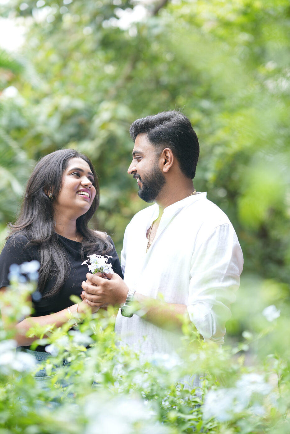Navya and Subramanya holding white flowers, smiling at each other
